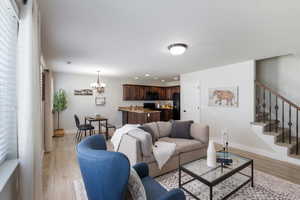 Living area featuring a chandelier, light wood-style floors, stairway, and recessed lighting