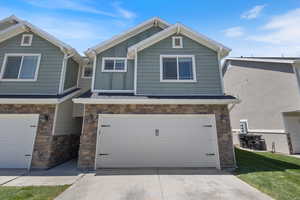 Craftsman house featuring stone siding, a garage, driveway, and board and batten siding