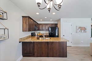 Kitchen featuring dark brown cabinets, black appliances, recessed lighting, a peninsula, and light wood-style flooring
