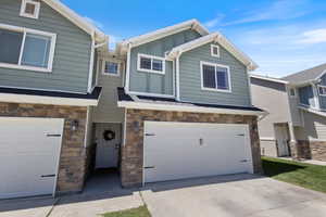 Craftsman house with stone siding, board and batten siding, a garage, and concrete driveway