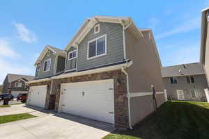 View of front of house with stone siding, a garage, and concrete driveway