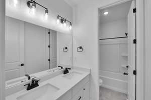 Bathroom with double vanity, tile patterned flooring, and bathing tub / shower combination