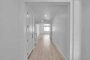 Hallway with light wood-style flooring and baseboards