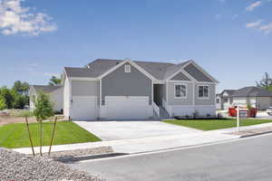 View of front of home featuring driveway, a front lawn, and an attached garage
