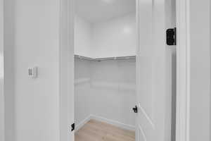 Walk in closet with light wood-type flooring