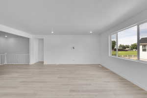 Empty room with light wood-style floors and recessed lighting