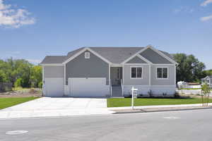 View of front of house featuring a front lawn, concrete driveway, and an attached garage