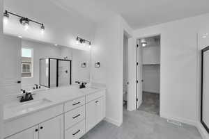 Full bath with a shower stall, double vanity, a walk in closet, and tile patterned floors