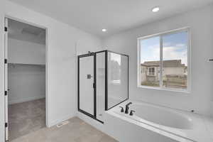 Bathroom with a stall shower, a garden tub, a walk in closet, tile patterned flooring, and recessed lighting