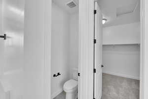 Bathroom featuring toilet and a walk in closet
