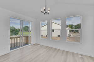 Unfurnished dining area with a chandelier, lofted ceiling, and wood finished floors