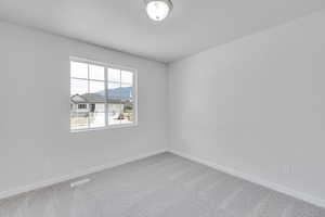 Carpeted spare room featuring baseboards