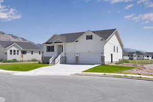 Modern farmhouse style home with an attached garage, concrete driveway, a mountain view, and a front yard