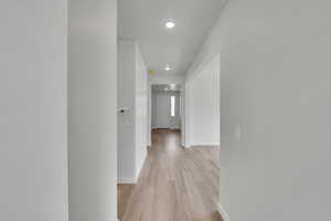 Hallway with light wood-type flooring and recessed lighting