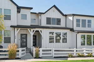 Modern inspired farmhouse featuring board and batten siding, a fenced front yard, and a porch