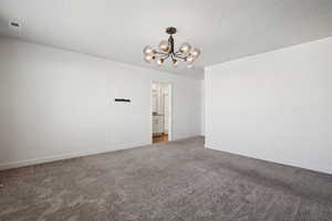 Unfurnished room with carpet floors, a chandelier, and a textured ceiling