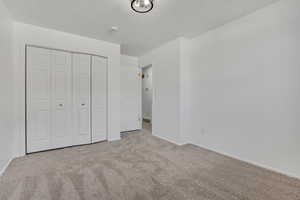 Unfurnished bedroom featuring carpet, a textured ceiling, and a closet