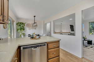 Kitchen featuring dishwasher, light wood finished floors, brown cabinetry, a peninsula, and light countertops