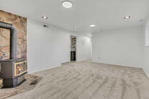 Unfurnished living room with a wood stove, carpet floors, and recessed lighting