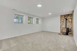 Below grade area featuring a wood stove, carpet flooring, and recessed lighting