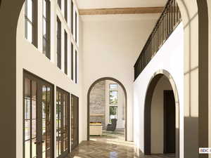 Hall featuring arched walkways, a high ceiling, and french doors