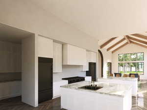 Kitchen with beamed ceiling, an island with sink, high end fridge, high vaulted ceiling, and white cabinetry