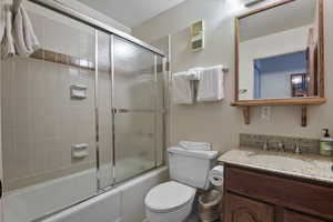 Bathroom with vanity and bath / shower combo with glass door