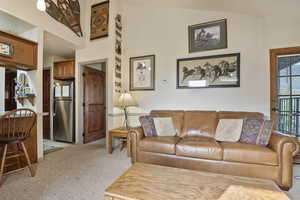 Living area with light colored carpet and vaulted ceiling