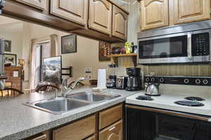Kitchen featuring range with electric stovetop, stainless steel microwave, light countertops, and open shelves