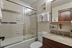 Bathroom featuring vanity, enclosed tub / shower combo, and a textured wall