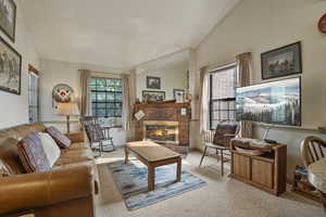 Living area with vaulted ceiling, carpet floors, and a fireplace