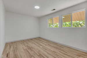 Spare room featuring light wood-type flooring and baseboards