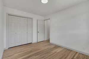 Unfurnished bedroom featuring light wood-type flooring and a closet