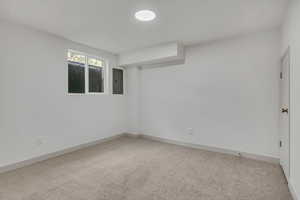 Carpeted spare room with baseboards and electric panel