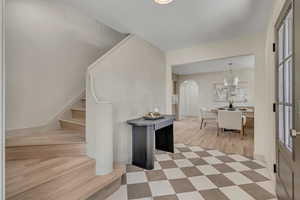 Entrance foyer featuring arched walkways, stairway, tile patterned floors, and a chandelier
