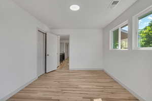 Empty room with light wood-type flooring and healthy amount of natural light