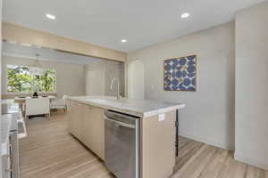 Kitchen with dishwasher, a center island with sink, light wood-style floors, stove, and recessed lighting