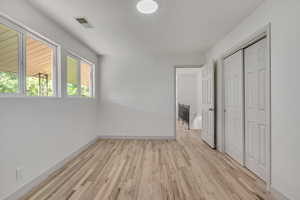 Unfurnished bedroom with light wood-style floors and a closet