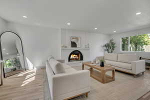 Living area with healthy amount of natural light, recessed lighting, light wood-type flooring, and a lit fireplace