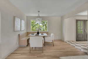 Dining space with healthy amount of natural light, light wood-style floors, and a chandelier
