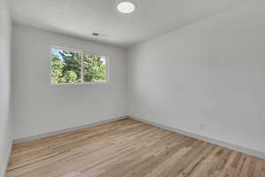 Unfurnished room with light wood-type flooring and a textured ceiling