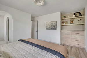 Bedroom with light wood-type flooring and arched walkways