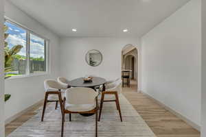 Dining space featuring light wood-style floors, arched walkways, and recessed lighting