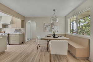 Dining space featuring arched walkways, light wood-style floors, and a chandelier