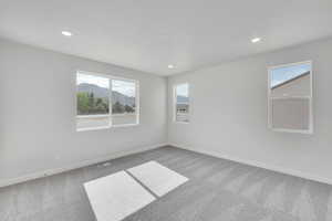 Carpeted empty room featuring recessed lighting and a mountain view