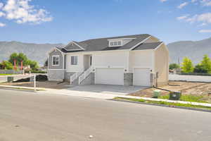 Craftsman-style home featuring a mountain view, stone siding, board and batten siding, concrete driveway, and a shingled roof