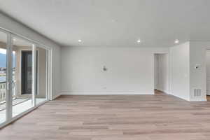 Empty room featuring light wood-style floors, a textured ceiling, and recessed lighting