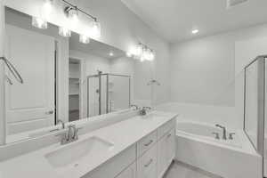 Bathroom featuring a shower stall, double vanity, a garden tub, a spacious closet, and recessed lighting