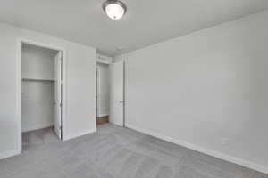 Unfurnished bedroom with carpet and a walk in closet