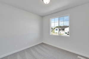 Carpeted spare room featuring baseboards